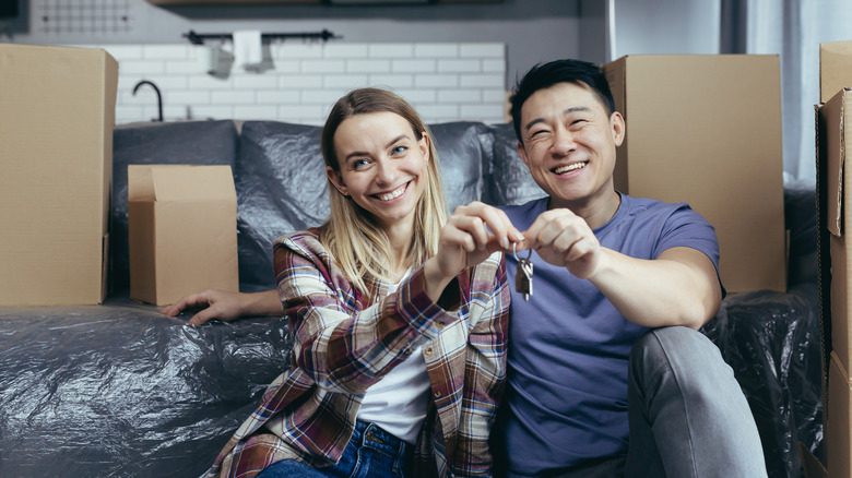 couple holding keys near moving boxes