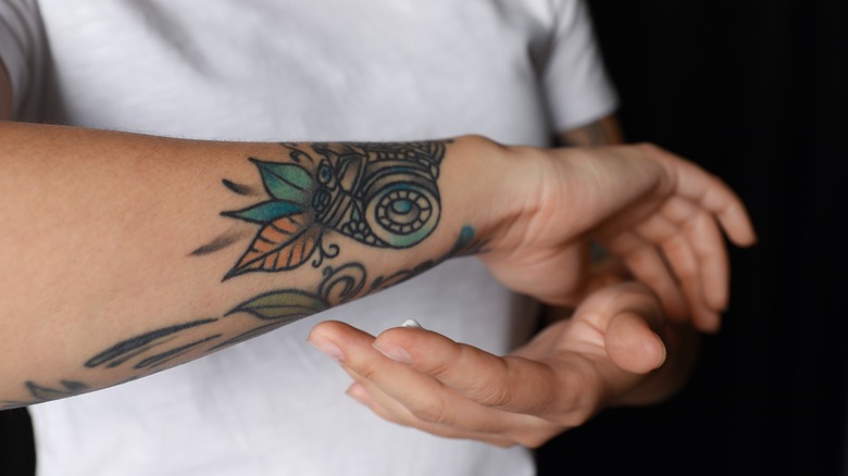 Woman applying antibiotic on tattoo