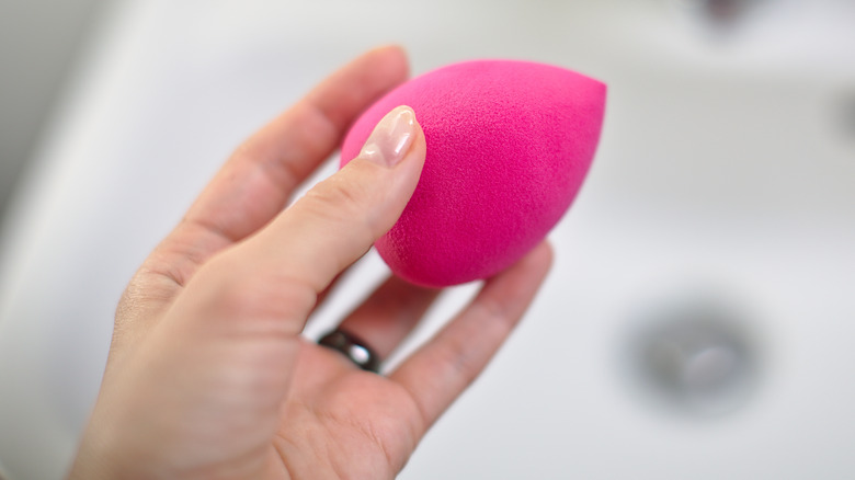 Hand holding pink beauty blender