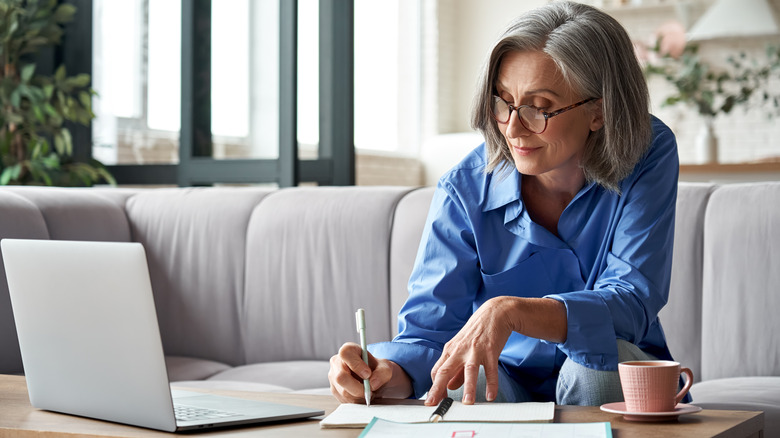 A woman working on her computer while sitting on her couch 