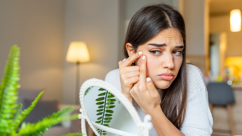 A woman trying to squeeze a pimple. 