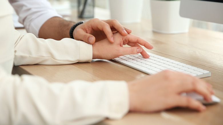 man touching woman's hand at desk