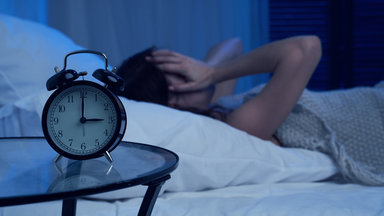 Woman can't sleep, alarm clock on side table
