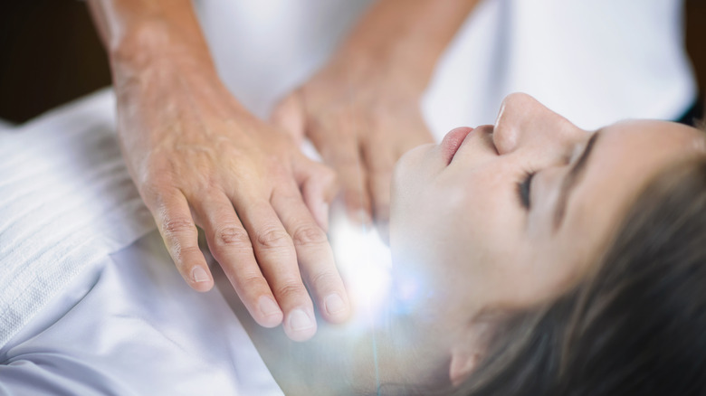 Person healing woman's throat chakra