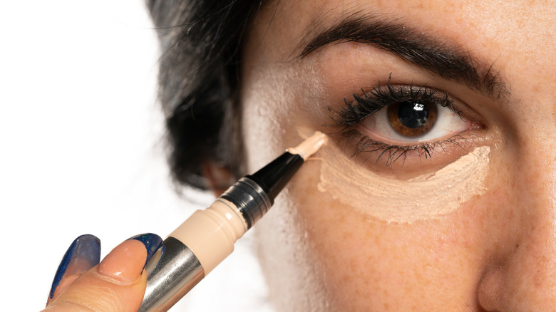 woman applying concealer under eye