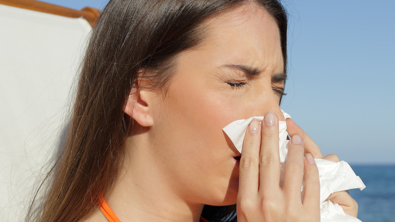 woman wiping nose on beach