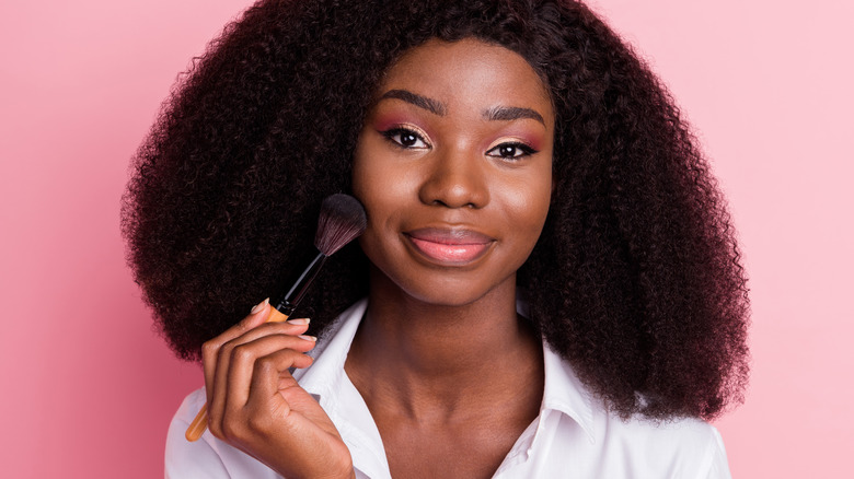 Woman applying blush on cheek