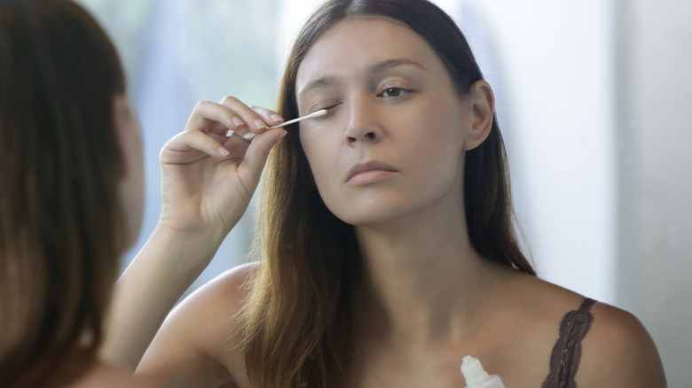 Woman putting on eyelash serum