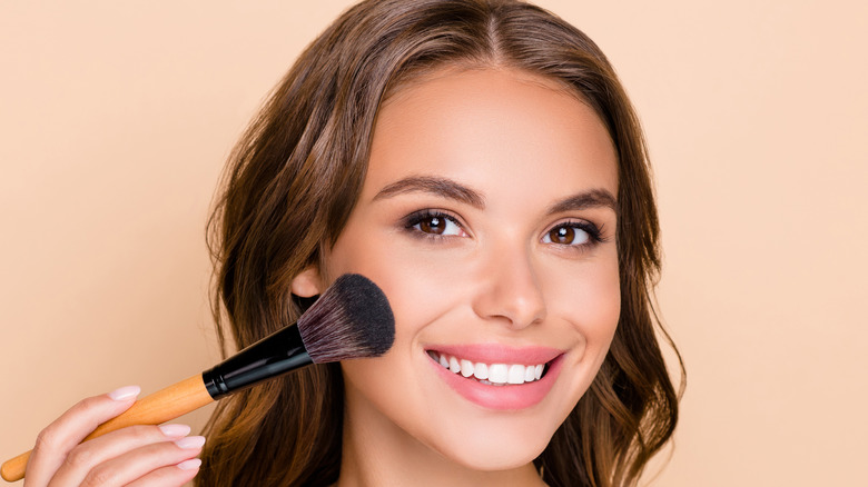 Woman applying makeup with contour brush