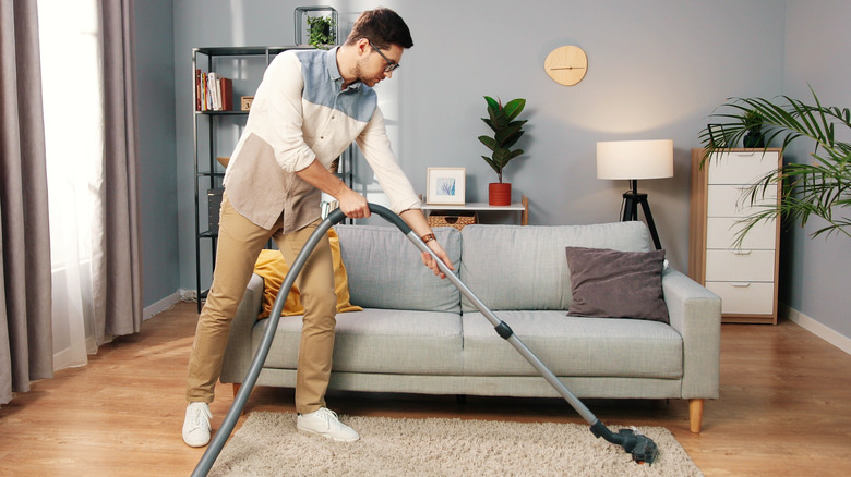 Man vacuuming area rug