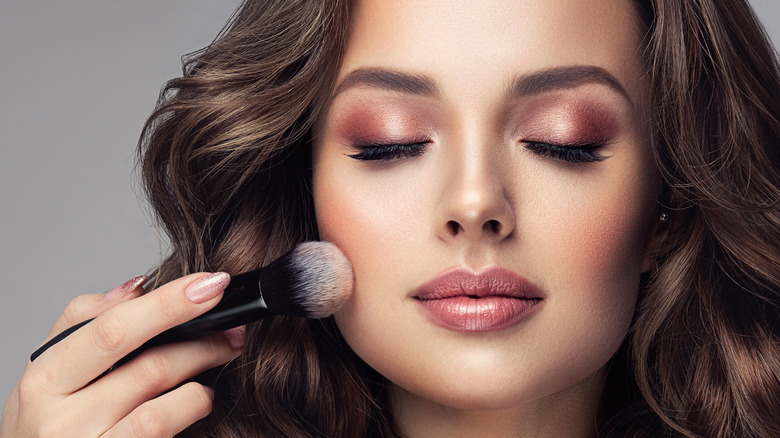 Woman applying powder to her face