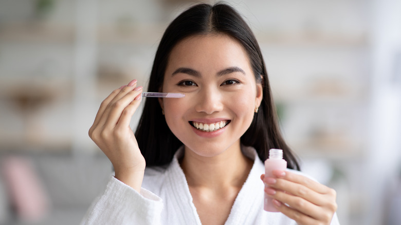 A woman holding a skin serum in her hand.