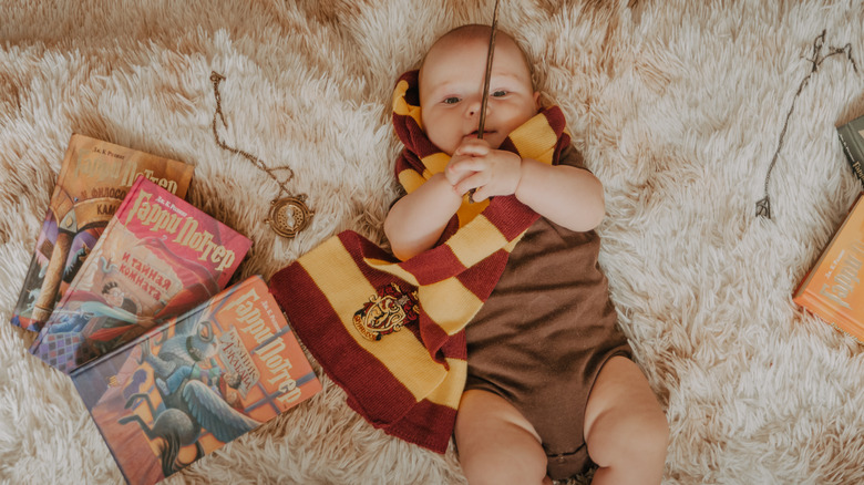 Baby holding wand next to Harry Potter books