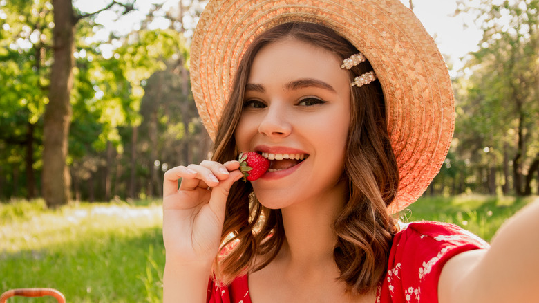 A brunette eating a strawberry