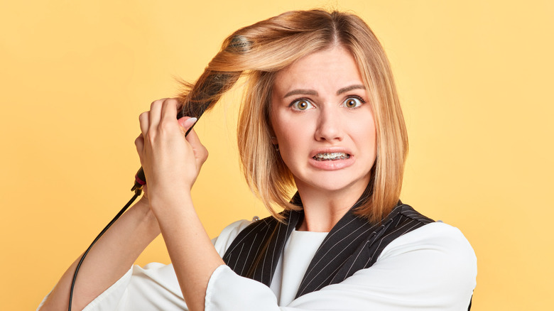 Woman realizing she burnt her hair with iron