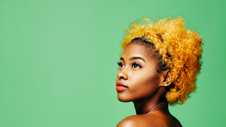 young woman with curly hair bleached from dark brown to blonde