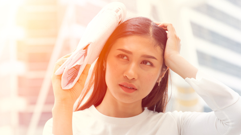 woman shielding her face from the sun with a newspaper