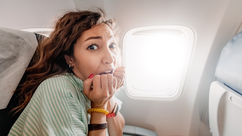A woman looking anxious in a plane seat 