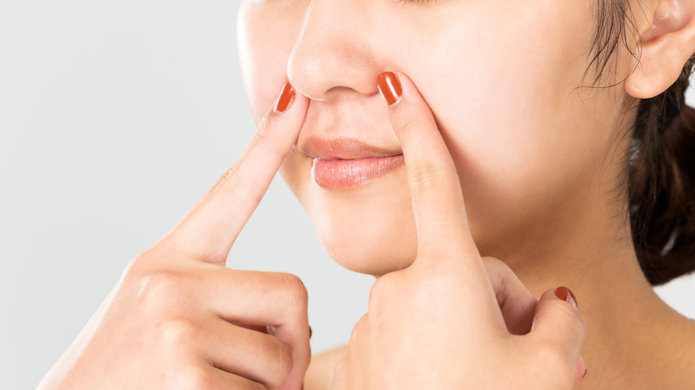 Woman gesturing to blackheads on nose 