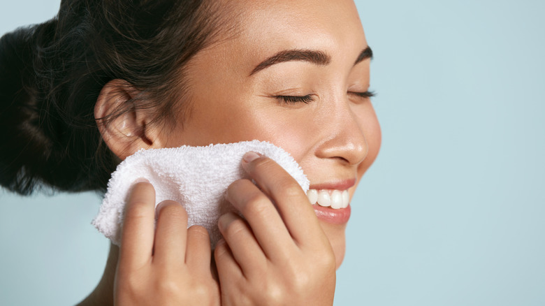 A woman using a soft cloth on her face 