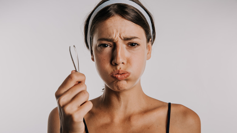 Woman holding a pair of tweezers 