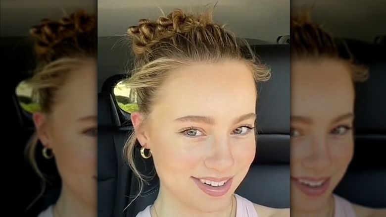 TikToker smiling with hair in funnel cake bun