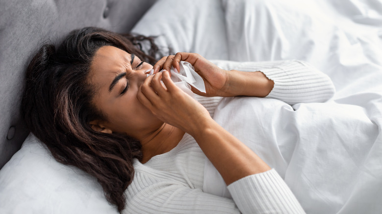 woman suffering from running stuffy nose and sore throat in bed