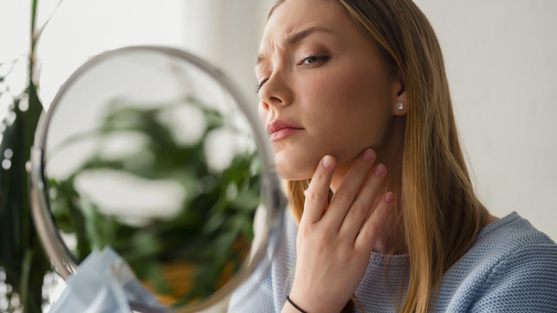 woman looking concerned in mirror