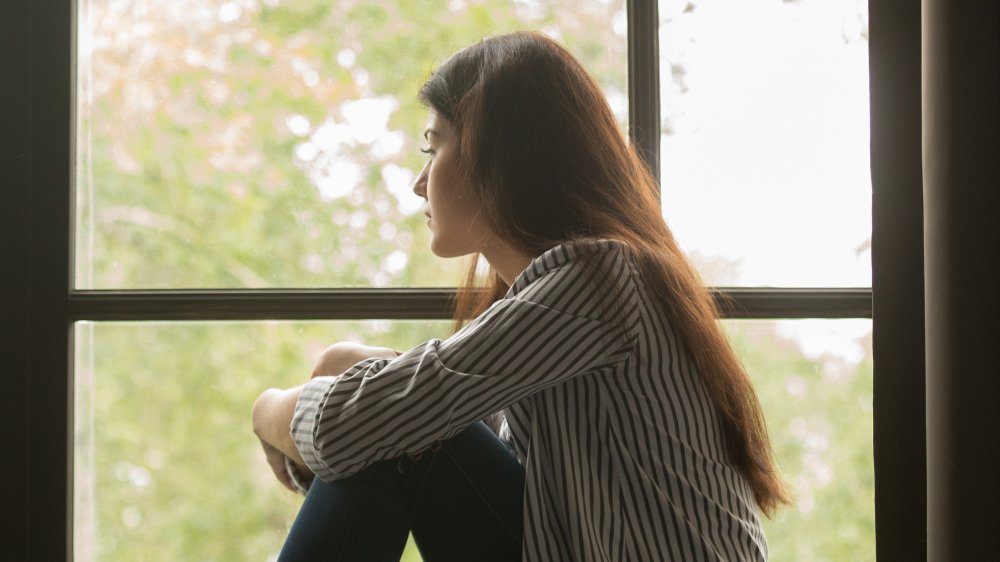 lonely woman sitting by a window