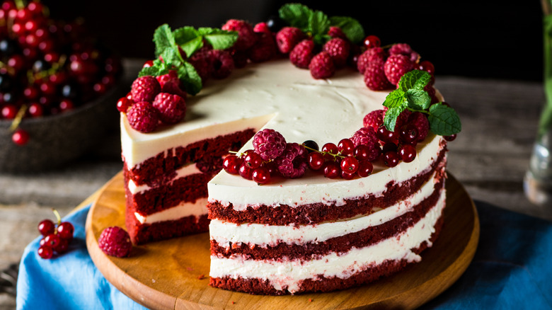 A red velvet cake topped with berries and cream