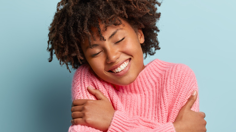 Self-hugging in cozy pink sweater