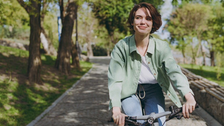 woman rides bicycle wearing green shacket 