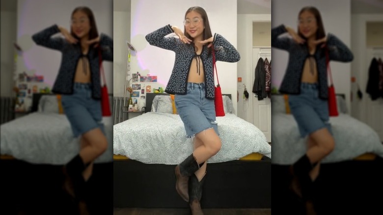 Woman wearing denim shorts, boots, and cardigan