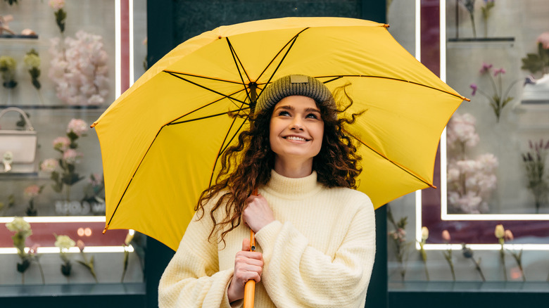 Woman with curly brown hair under yellow umbrella
