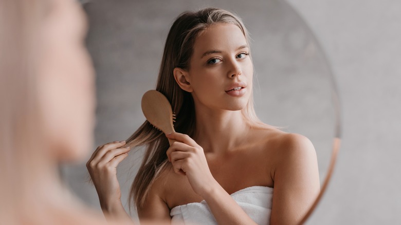 Woman in towel brushing her hair in a mirror