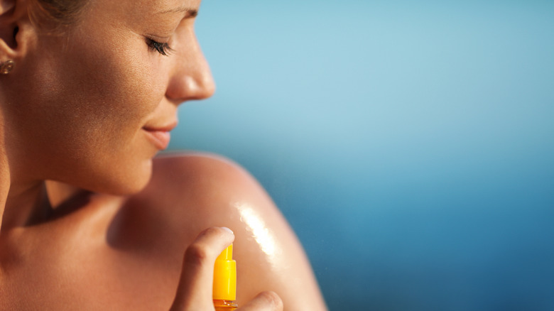 Woman spraying on sunscreen