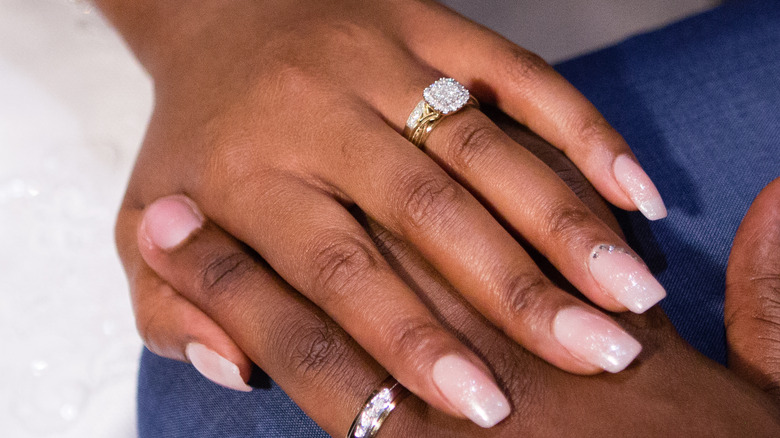 A woman in a pink sweater showing her engagement ring 