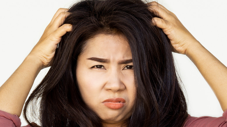 Brunette woman scratching her scalp