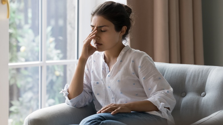 Woman sitting with hand on face