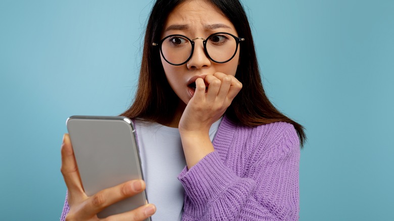 woman looking at phone scared