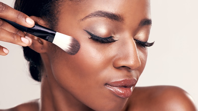 Woman with makeup brush on face