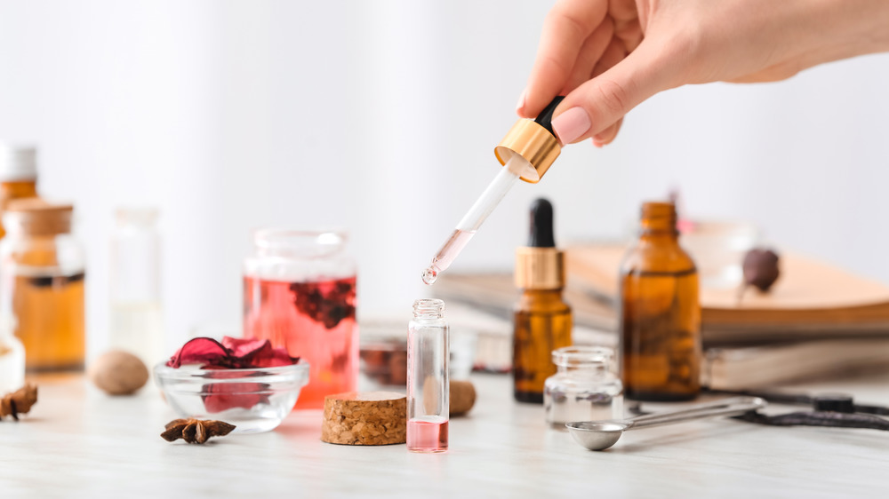 A hand dropping essential oils into a container 