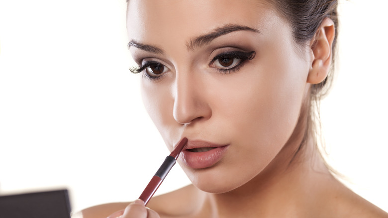 Closeup applying brown lip liner