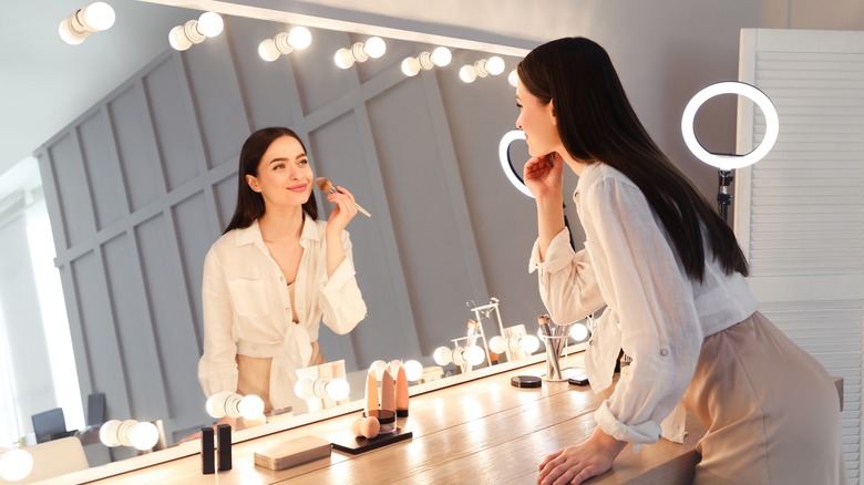 Woman applying makeup in mirror