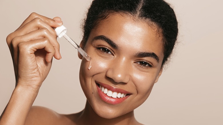 Woman applying serum to face