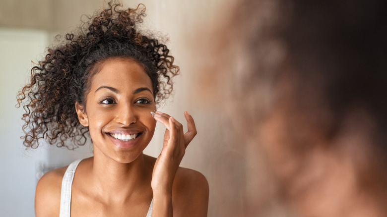 Woman smiling and applying moisturizer 