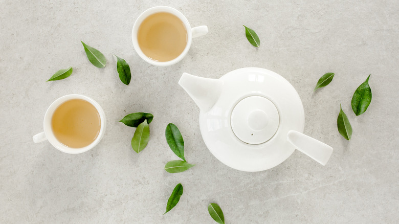 A teapot with teacups and leaves