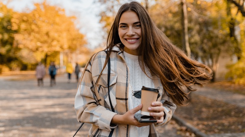 A woman smiling while holding a coffee