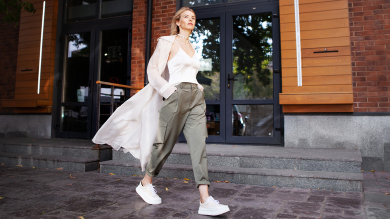 A woman strides down the street wearing cargo pants.