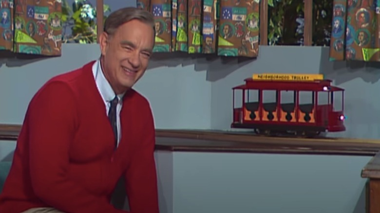 Tom Hanks as Mister Rogers in red cardigan